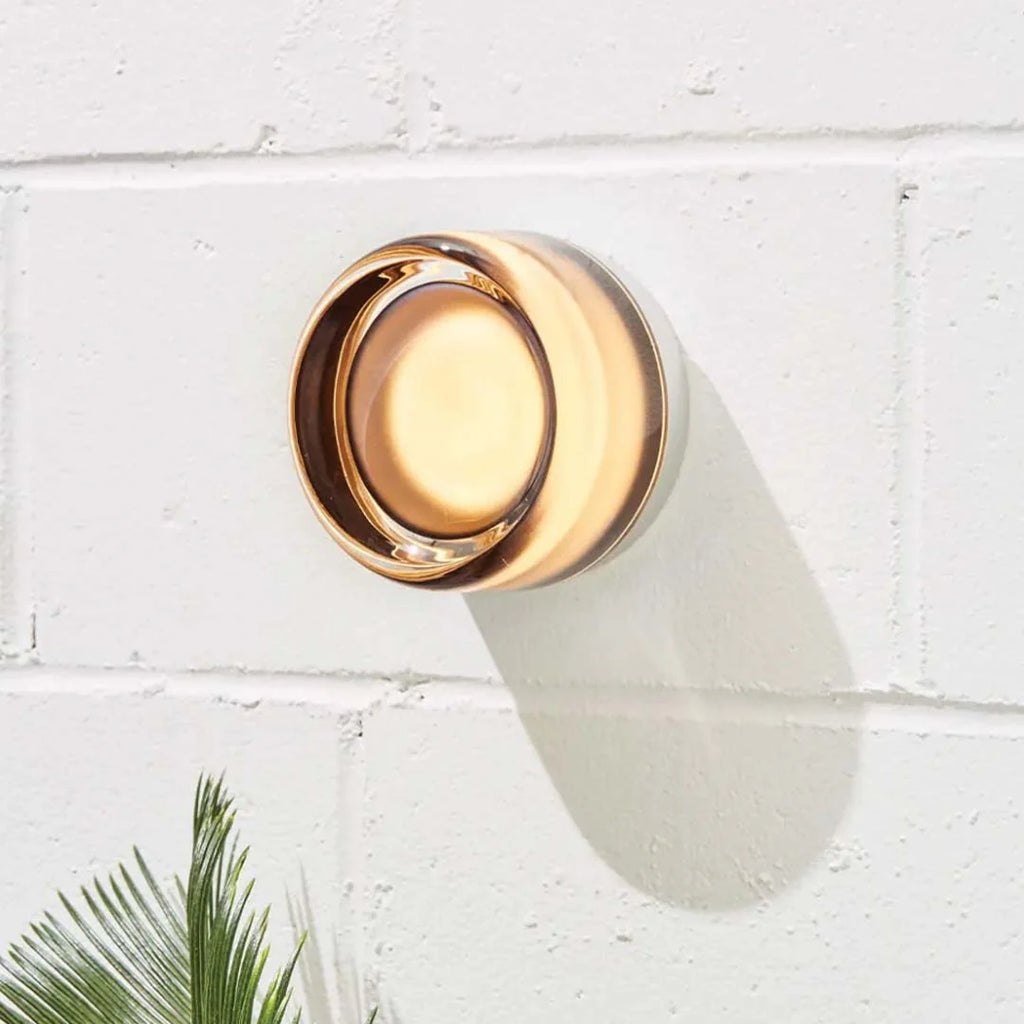 Compact Curved Wall Light - Smoke Version Lit on Painted Brick