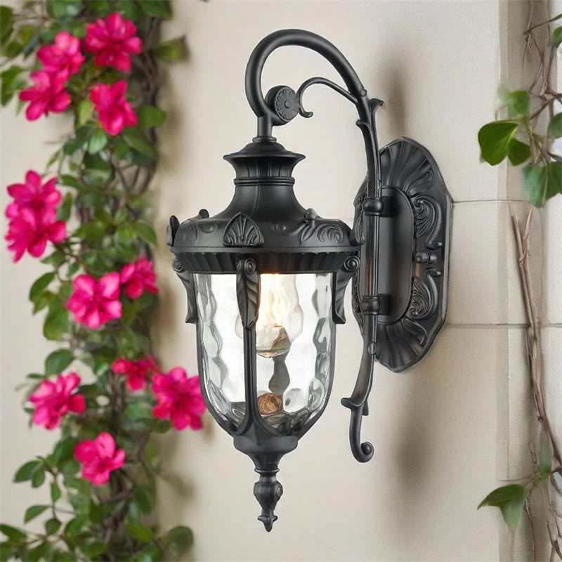 Vintage Outdoor Wall Lantern with Scroll Arm - Black Finish Beside Climbing Flowers