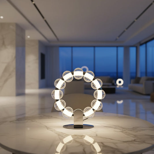 Lorvali Amulet table lamp with a circular ring of smoke gray glass beads and integrated LED lighting on a marble table.