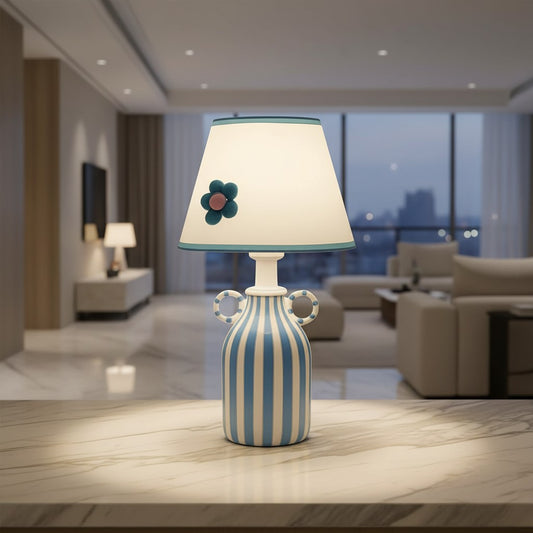Lorvali Blumelo table lamp with a ceramic striped base and a fabric shade featuring a handcrafted blue felt flower.