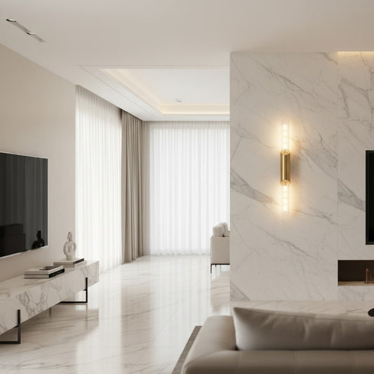 Lorvali cylindrical brass wall light with transparent glass shades mounted on a marble wall in a modern living room.
