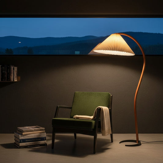 Lorvali Caprani floor lamp with a sinuous beech wood frame and pleated shade next to a green armchair at night