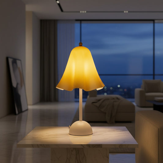 Lorvali Colette table lamp with an amber ruffled glass shade and white metal base, glowing on a marble side table.