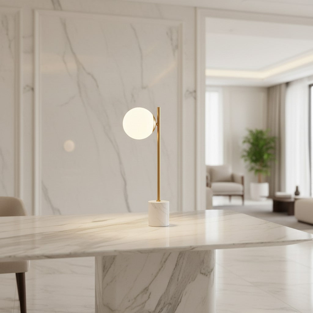 Lorvali Domo table lamp with a white glass globe, gold iron stem, and marble base on a matching marble table.