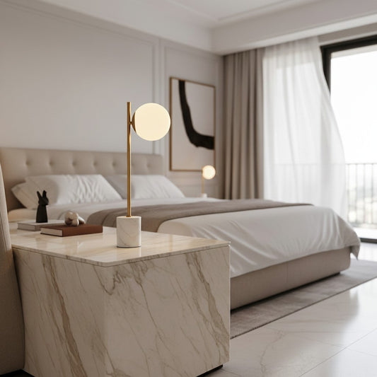 Lorvali Domo table lamp with a gold stem, white glass globe shade, and marble base on a marble bedside table in a bedroom