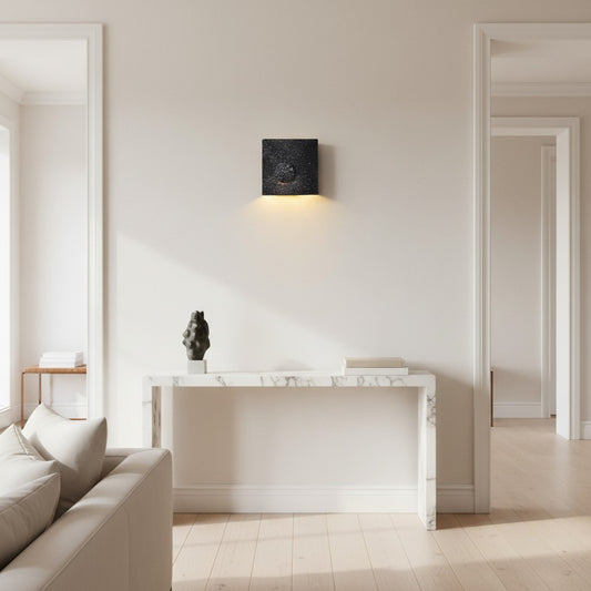 Lorvali frosted black cement square LED wall light mounted above a marble console table in a modern living room.