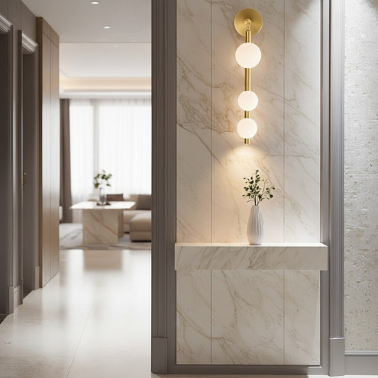 Lorvali modern gold wall light with three milky white glass globes mounted on a marble wall in a luxury hallway