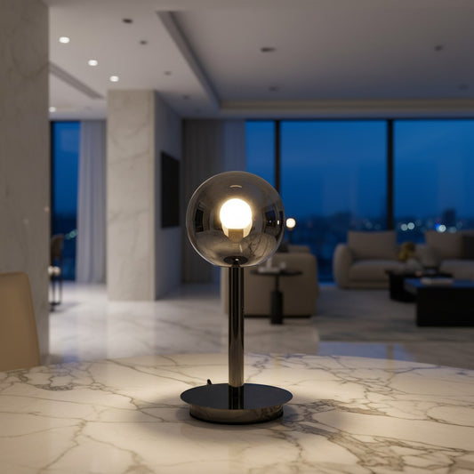 Lorvali Luna modern table lamp with a smoke gray glass sphere and integrated LED light on a marble table.