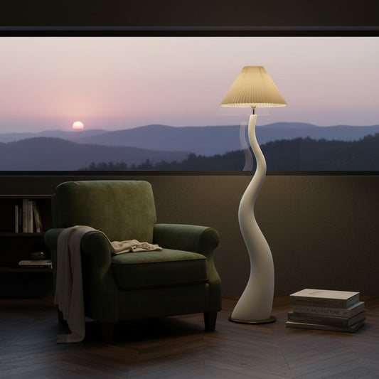 Lorvali Marlene twisted floor lamp with a white resin base and pleated shade next to a green armchair at sunset.