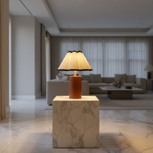 Lorvali Martin table lamp with a walnut wood base and pleated white fabric shade, set on a marble pedestal.