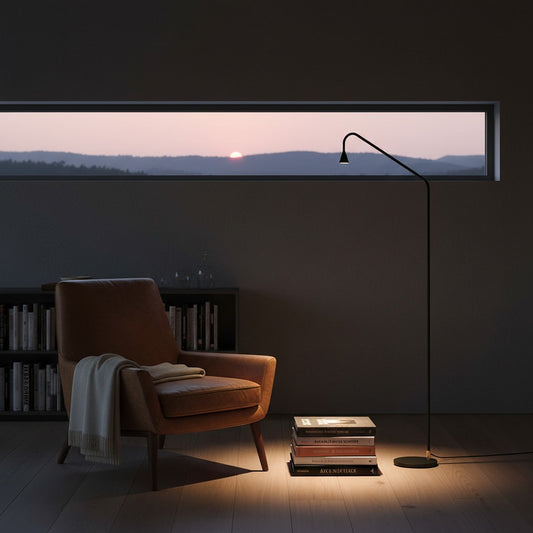 Lorvali minimalist black and gold LED floor reading lamp casting a warm glow next to a leather armchair in a cozy room.