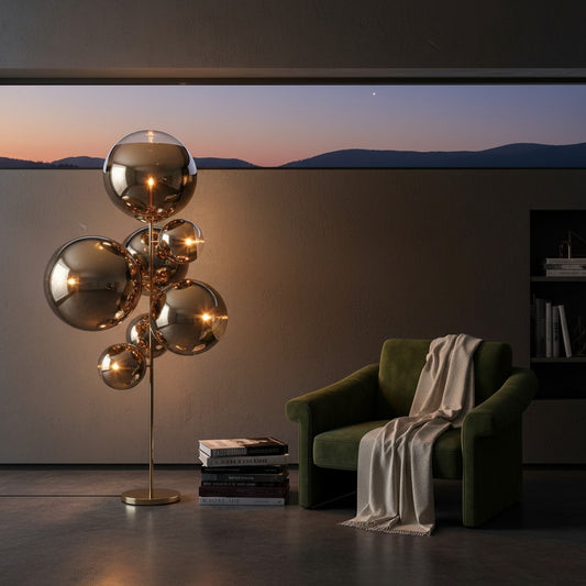 Lorvali Mirror Ball floor lamp with reflective gold glass spheres next to a green velvet armchair in a modern room.