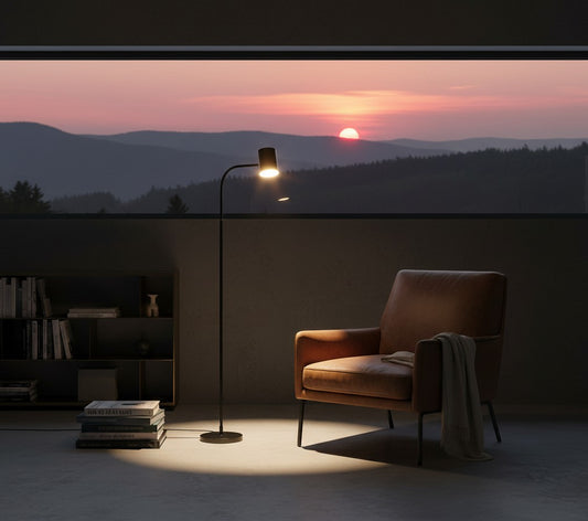 Lorvali modern black floor reading lamp with adjustable neck illuminating a leather armchair at sunset