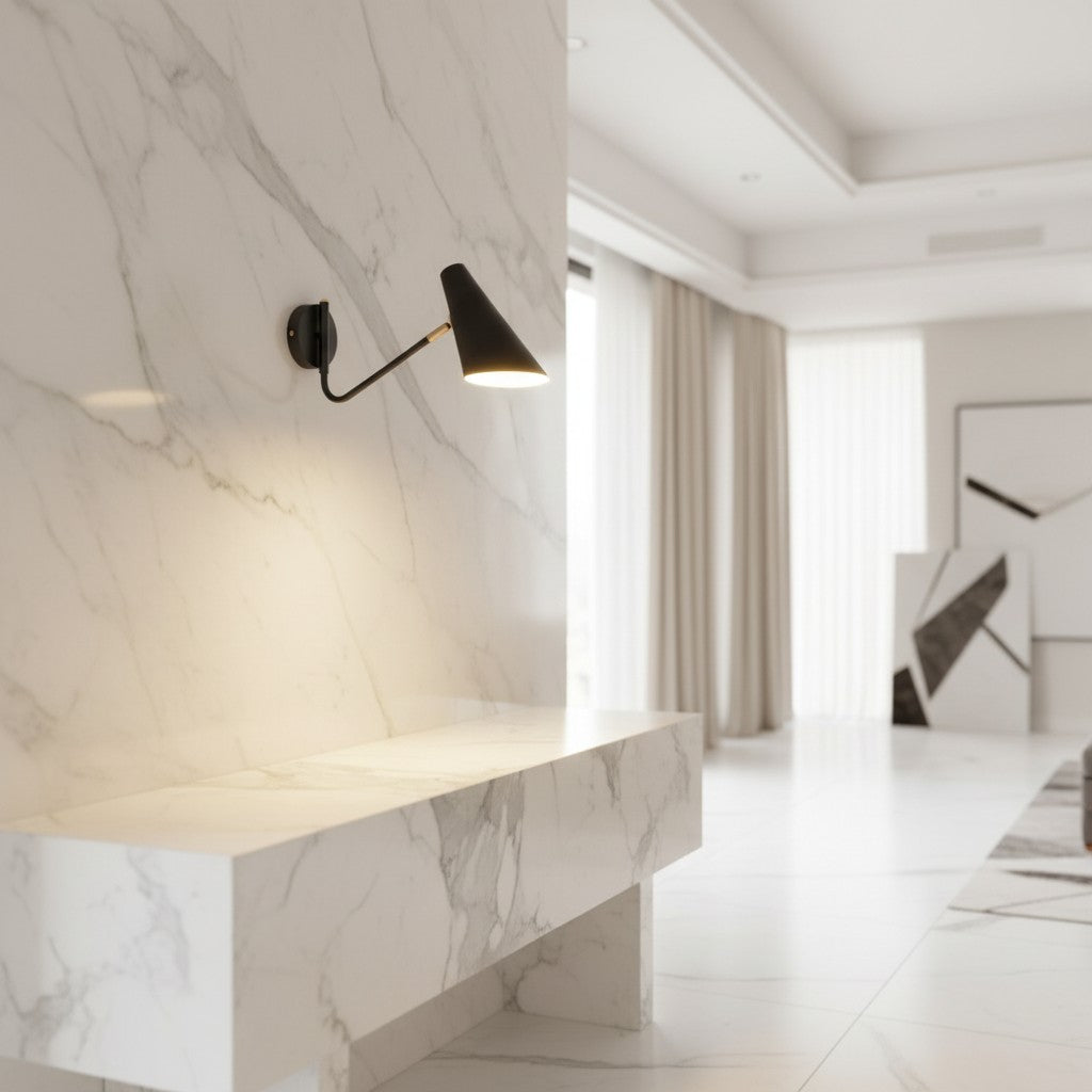 Lorvali modern black swing arm wall sconce with conical shade mounted on a white marble wall in a bright room
