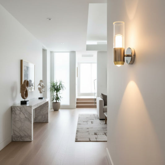 Lorvali modern gold and black wall light fixture with acrylic cylinder shade mounted in a bright minimalist hallway