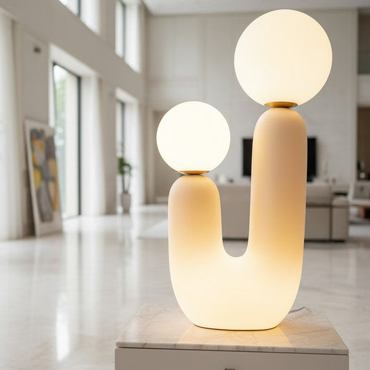 Lorvali Oo modern white ceramic table lamp with two glowing glass globes on a marble pedestal in a bright room