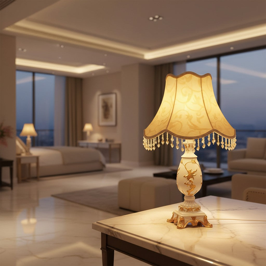 Lorvali Petunia resin table lamp with gold accents, beige fabric shade, and dangling beads in a luxury bedroom.
