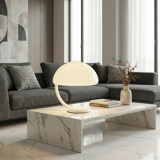 Lorvali Serpente modern white iron and acrylic table lamp with a sculptural dome shade on a marble coffee table.