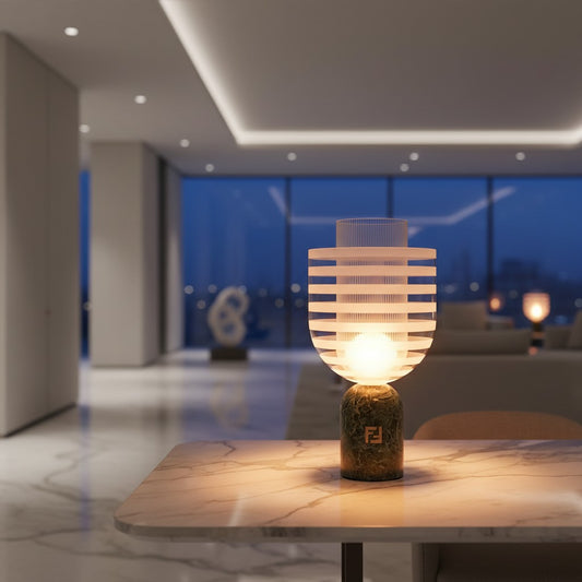 Lorvali Striara modern table lamp with green marble base and clear Murano glass shade on a marble table at night.