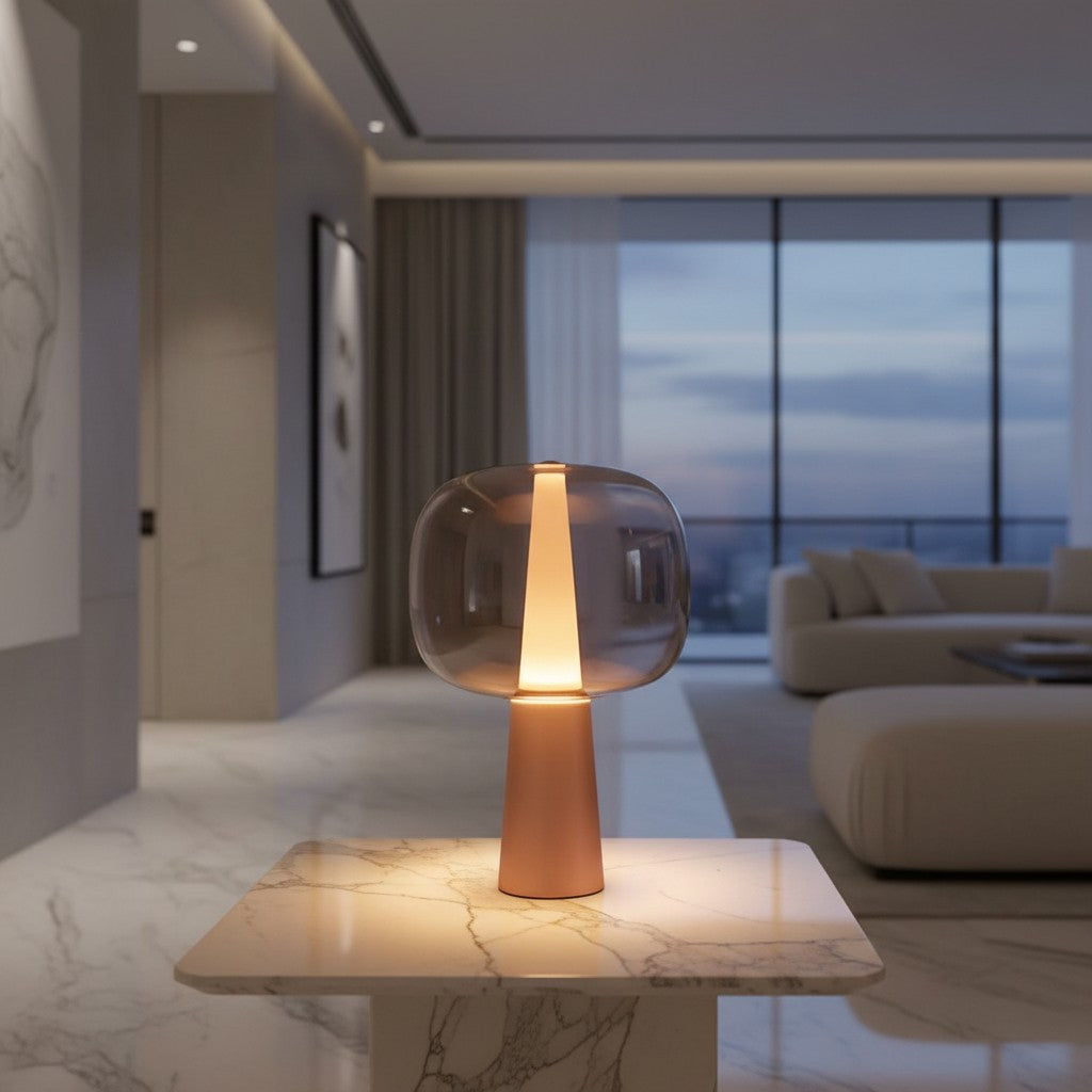 Lorvali Sunset Glass Table Lamp with a smoke gray glass shade and rose gold tapered base on a marble table.