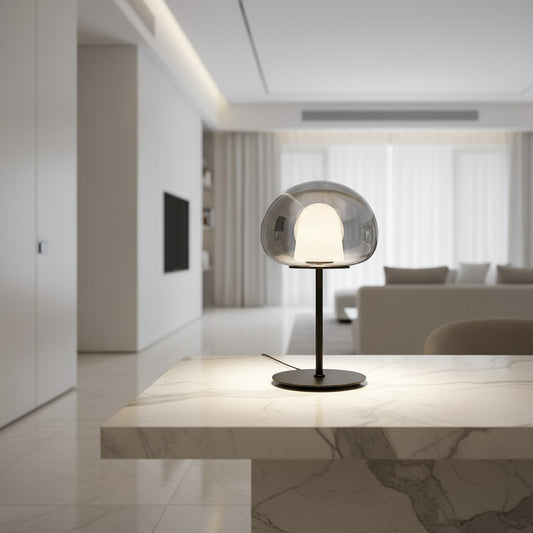 Lorvali Thea table lamp with a smoke gray glass dome shade and black metal base on a marble table in a modern room.