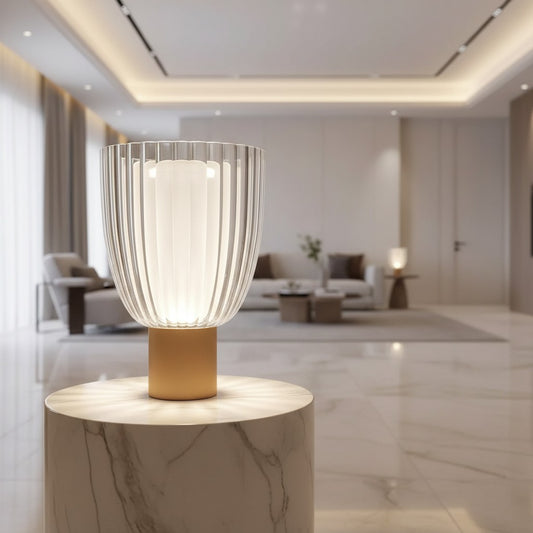 Lorvali Universal Table Lamp with a modern gold metal base and clear fluted glass shade on a marble pedestal